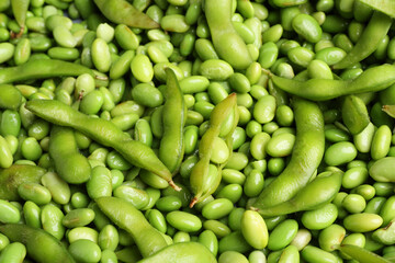 Fresh edamame beans and pods as background, above view