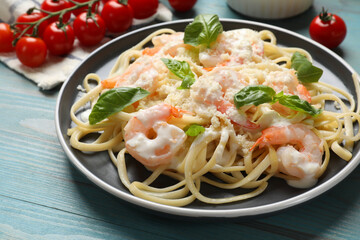 Tasty pasta with shrimps on light blue wooden table, closeup