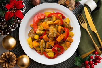Stir-fried chicken with sweet potato and red pepper. Top view table with Christmas decorations.