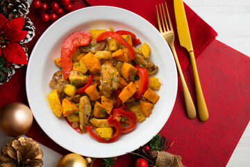 Stir-fried chicken with sweet potato and red pepper. Top view table with Christmas decorations.