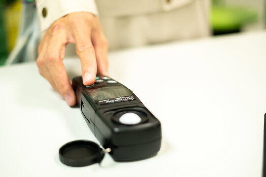 An electrical worker's hand is holding a light meter in the workplace, lighting, light meter, occupational safety, occupational health, office electric light