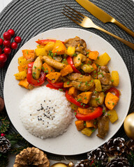 Stir-fried chicken with sweet potato and red pepper. Top view table with Christmas decorations.