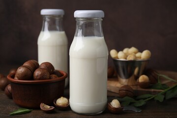 Bottles of macadamia milk and nuts on wooden table, closeup