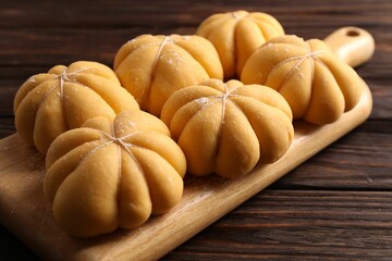 Raw pumpkin shaped buns on wooden table, closeup