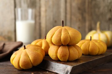 Tasty pumpkin shaped buns on wooden table, closeup