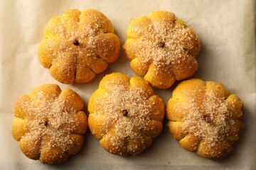 Tasty pumpkin shaped buns on parchment, top view