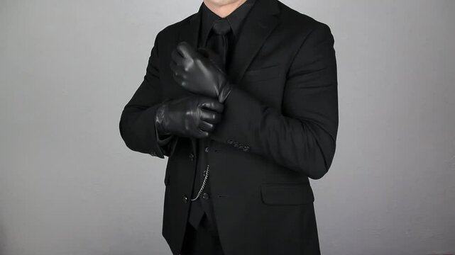 Mysterious Man in Dark Suit Pulling on Leather Gloves Menacingly. Mafia Hit Man or Violent Gangster. Threat of Danger.