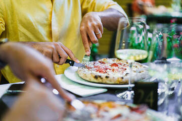 Person eating pizza outdoors - Italian food lifestyle and dining experience with wine and friends