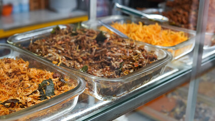 Food stalls called warteg share a variety of buffet traditional menus of indonesia with vegetables, chicken curry sauce, beef, eggs, tofu, tempeh. Menu in glass display case. 