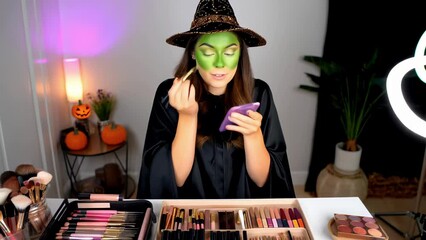 Beauty blogger girl Green Witch face paint makeup tutorial, showing finished look makeup products on table, Halloween fancy dress party ideas