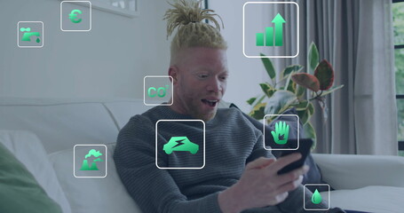 Image of eco icons and data processing over albino african american man using smartphone at home