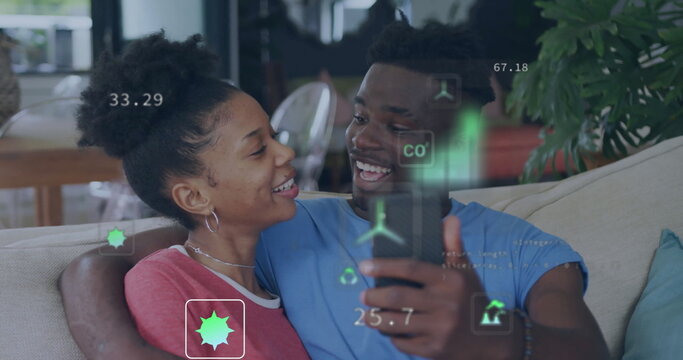 Image of eco icons and data processing over happy african american couple using smarthopne