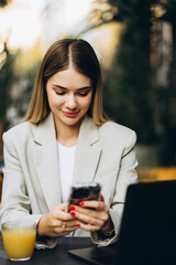 Young business woman sitting in a cafe drinking juice and working on a computer