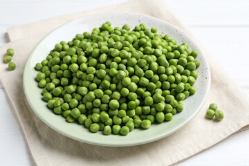 Fresh green peas in plate on white wooden table