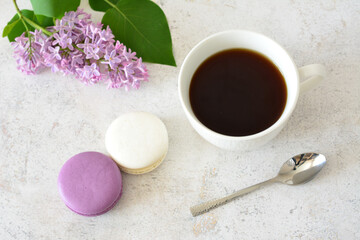 a cup of coffee and a purple lilac flower with white and purple macaroons