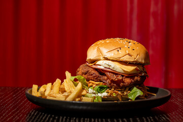 delicious giant burger on a black table and red background