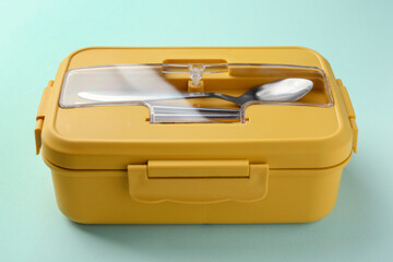 One lunch box with cutlery on light blue background