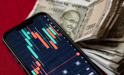Indian 500 rupee currency bank note against share market chart on a display