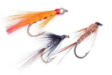 Group of three fishing flies in orange, black and tan brown isolated on white background. Concept angling, sport, leisure, outdoors.