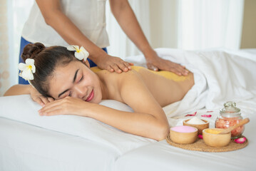 Young Asian woman enjoying in spa salon, Beauty therapist pouring scrub on woman back at health spa