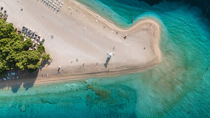 Visitors stroll along the sandy shores of Brac Island, surrounded by crystal-clear waters. The vibrant atmosphere invites relaxation and adventure on a beautiful sunny day. Zlatni Rat Beach Croatia