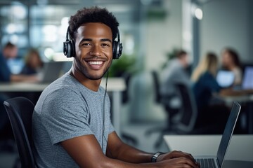 Fototapeta premium Young man smiling while working on a laptop in a busy office