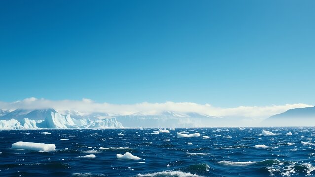 Icebergs float in the ocean under a bright blue sky.