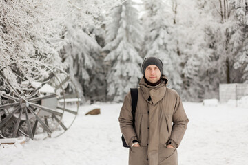 Portrait of young man in warm clothes in winter forest. Hiking. Tourism.