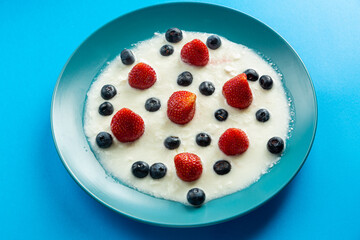 Berries juicy strawberries and blueberries in a blue plate with cream