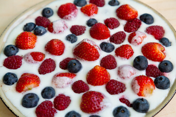 In a plate with whipped cream, fresh berries strawberries, raspberries and blueberries