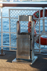 a metal trash bin and a smoking area on the ship's promenade deck