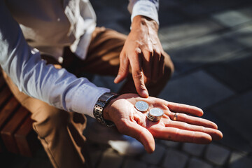 A man confidently and proudly showcases his collection of valuable coins in one hand, gesturing with his index finger to emphasize their significance, beauty, and historical value