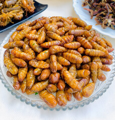 A plate of golden brown fried silkworm pupae, a traditional snack