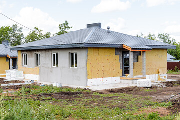 At this moment in time, a house is actively under construction in the very center of a stunning, expansive field, surrounded by vibrant green grass and the bright, clear blue sky above