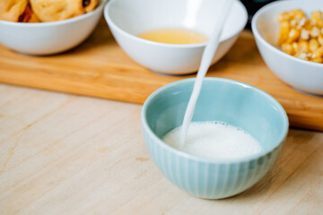 A delightful, creamy bowl of fresh milk is being gracefully poured into a second bowl, with a shiny spoon thoughtfully placed beside it to elevate the entire meal experience wonderfully