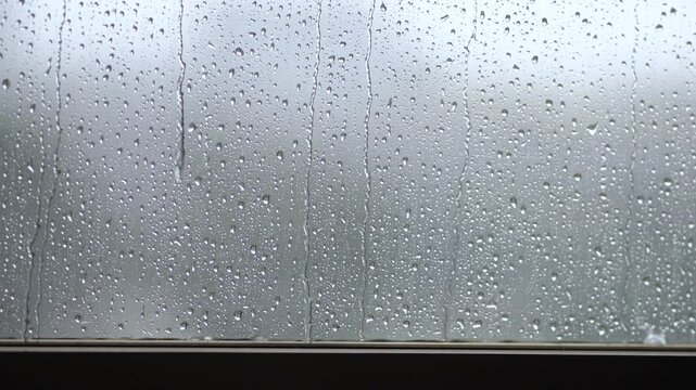 Rainy autumn weather, shower in fall, September, October, November. Inside view of window with dripping water, droplets falling outside. Dreary melancholic mood, sad upset emotions feelings concept.