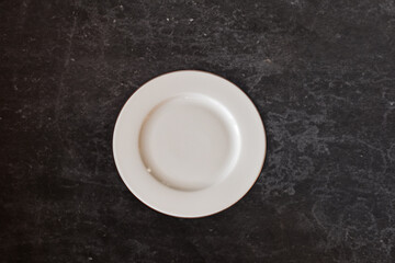 Ceramic white flat plate for food on black table top view
