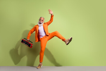 Full body portrait of funky eccentric handsome grandfather dance boombox wear orange suit isolated on green color background