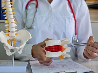 Doctor traumatologist and surgeon shows herniated disc female patient in clinic concept