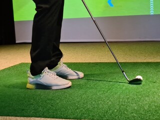 Golf swing practice indoors on artificial turf with a focus on the player's grip and stance concept
