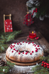 Traditional homemade christmas cake holiday dessert with cranberry and chocolate with new year tree decoration on vintage wooden table background. Rustic style.