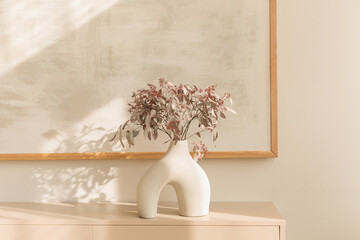A stylish modern vase with decorative branches on a sideboard  in a modern living room. © Nina
