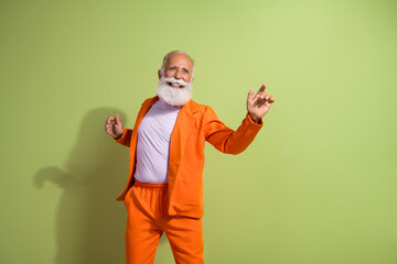 Fototapeta premium Portrait of funky eccentric grandfather dancing wear orange suit isolated on green color background