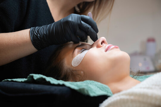 Beauty Close-up of a young woman having her eyelashes lash lifting enhanced with an eyelash lift by a beautician in a beauty salon. Shaping eye lash correction, color, curler, glue balm and mascara.