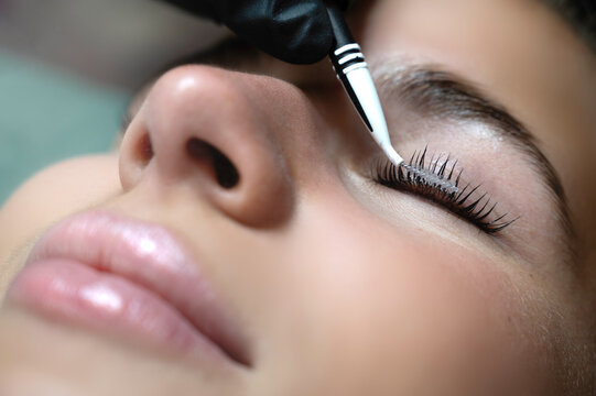 Beauty Close-up of a young woman having her eyelashes lash lifting enhanced with an eye lash lift by a beautician in a beauty salon. Shaping eyelash correction, color, curler, glue balm and mascara.