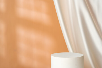 Minimalist decor featuring a white cylinder and draped fabric in a warm-toned interior with soft lighting