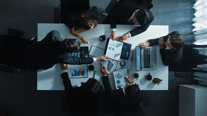 Top down aerial view of smart business man join meeting and present financial plan while diverse business people discuss and brainstorm marketing idea at table with marketing document. Directorate. © InfiniteFlow
