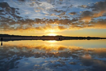 A stunning sunset over a calm lake, creating a beautiful reflection in the water.