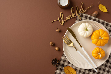 Top view of a Thanksgiving table setting with mini pumpkins, cutlery, and a thankful sign, symbolizing gratitude