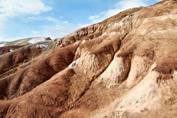 A rocky hillside with varied textures and colors under a blue sky.